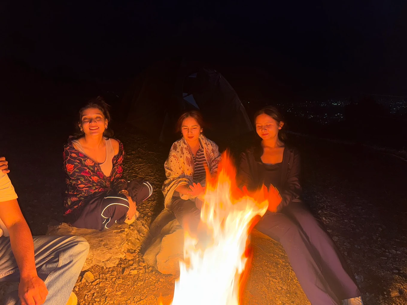 Friends around bonfire at night